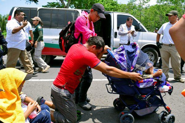 A migrant kneels while holding the stroller of his son after being detained by federal police officers during a joint operation by the Mexican government to stop a caravan of Central American migrants on their way to the United States, at Metapa de Dominguez, in Chiapas state, Mexico, on June 5, 2019. (Jose Torres/Reuters)