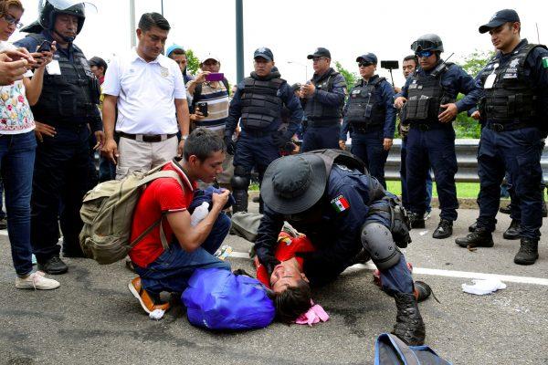 A federal police officer checks the head of an injured migrant during a joint operation by the Mexican government to stop a caravan of Central American migrants on their way to the U.S., at Metapa de Dominguez, in Chiapas state, Mexico, on June 5, 2019. (Jose Torres/Reuters)