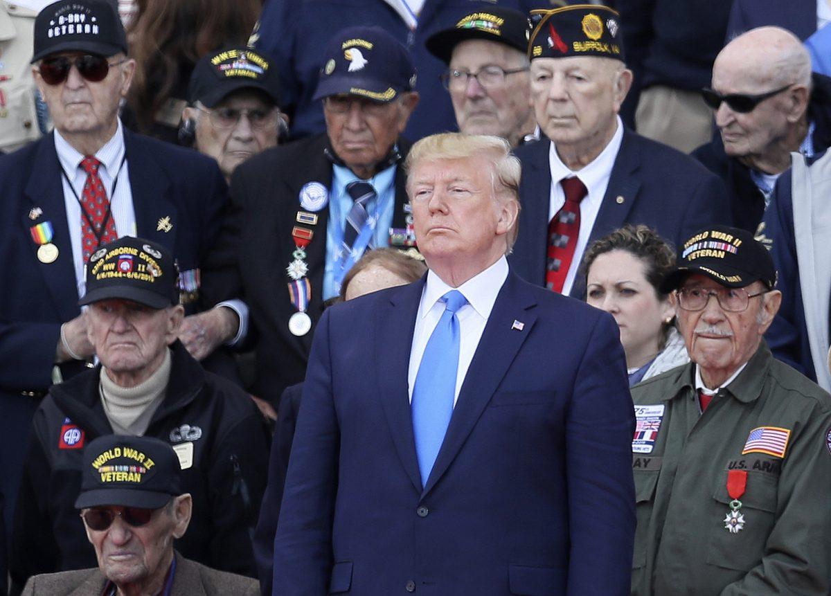 U.S. President Donald Trump stands with World War II veterans during a ceremony to mark the 75th anniversary of D-Day at the Normandy American Cemetery in Colleville-sur-Mer, Normandy, France, Thursday, June 6, 2019. World leaders are gathered Thursday in France to mark the 75th anniversary of the D-Day landings. (AP Photo/David Vincent)