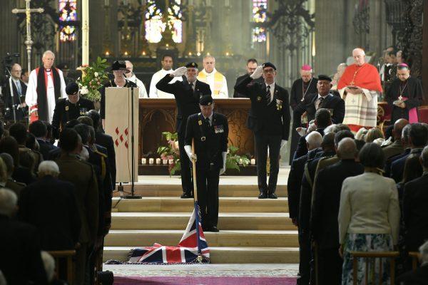 Bishop Jean-Claude Boulanger (R) looks at veterans lowering the Union Jack as they pay their respect during a ceremony at the Cathedral of Bayeux, Normandy on June 6, 2019. (Bertrand Guay/Pool via AP)