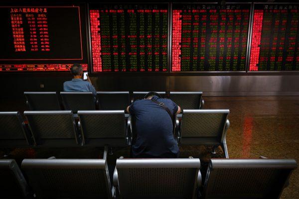 Investors rest on a chair in front of screens showing stock market movements at a securities company in Beijing on May 14, 2019. (Wang Zhao/AFP/Getty Images)