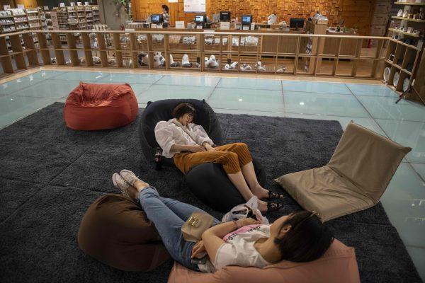 People take a nap inside a shop at a shopping mall in Beijing on May 17, 2019. (NICOLAS ASFOURI/AFP/Getty Images)
