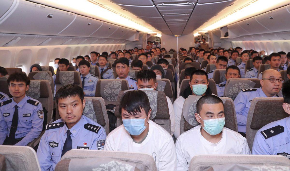 Police and criminal suspects extradited from Spain sit on a plane at Beijing Capital International Airport in Beijing on June 7, 2019. (Yin Gang/Xinhua via AP)