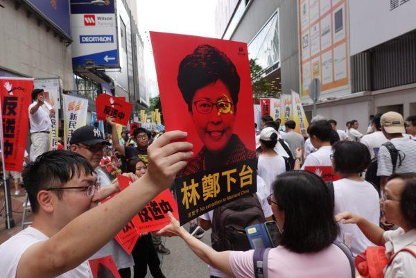 A protestor holds up a poster with the words "Carrie Lam Step Down" in Hong Kong on June 9, 2019. (Yu Gang/The Epoch Times)