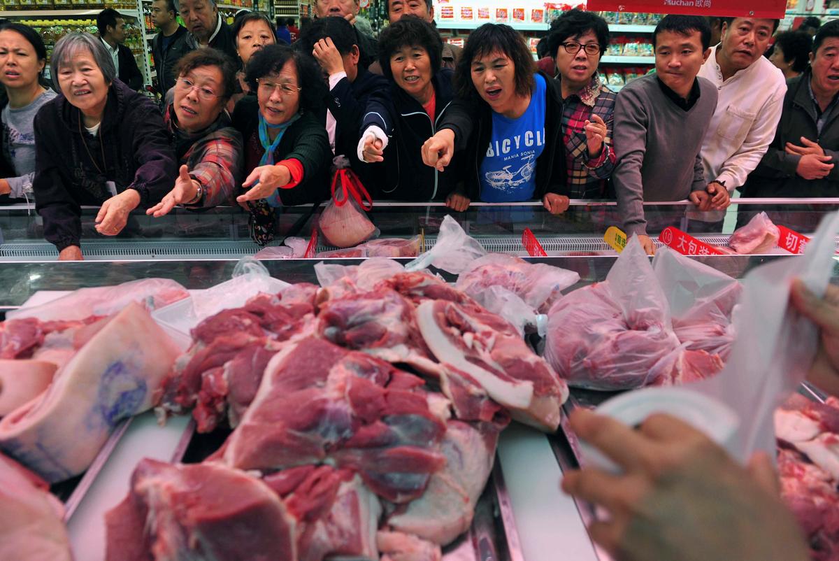 Customers point to chopped pork for sale during a promotional event at a supermarket in Shenyang, Liaoning Province, China on Nov. 9, 2012. (Reuters)