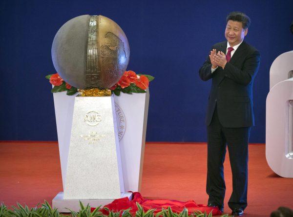 Chinese leader Xi Jinping applauds after unveiling a sculpture during the opening ceremony of the Asian Infrastructure Investment Bank (AIIB) in Beijing on Jan. 16, 2016. (AP Photo/Mark Schiefelbein, Pool)