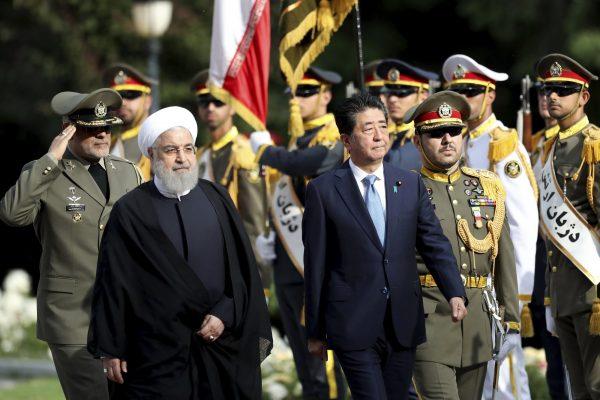 Japanese Prime Minister Shinzo Abe, center, reviews an honor guard as he is welcomed by Iranian President Hassan Rouhani, left, in an official arrival ceremony at the Saadabad Palace in Tehran, Iran on June 12, 2019. (Ebrahim Noroozi/Photo via AP)