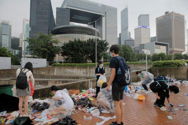 People clear rubbish outside the Legislative Council building after violent clashes during a protest against a proposed extradition bill with China in Hong Kong, on June 13, 2019. (Thomas Peter/Reuters)
