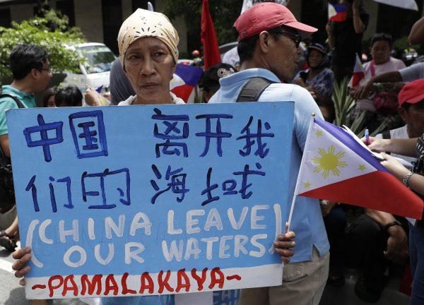 A protester holds a slogan during a rally outside the Chinese Consulate in the financial district of Makati, metropolitan Manila, Philippines, to mark Independence Day on June 12, 2019. The Philippine defense secretary says an anchored Filipino fishing boat has sunk in the disputed South China Sea after being hit by a suspected Chinese vessel, which then abandoned the 22 Filipino crewmen. (Aaron Favila/AP)