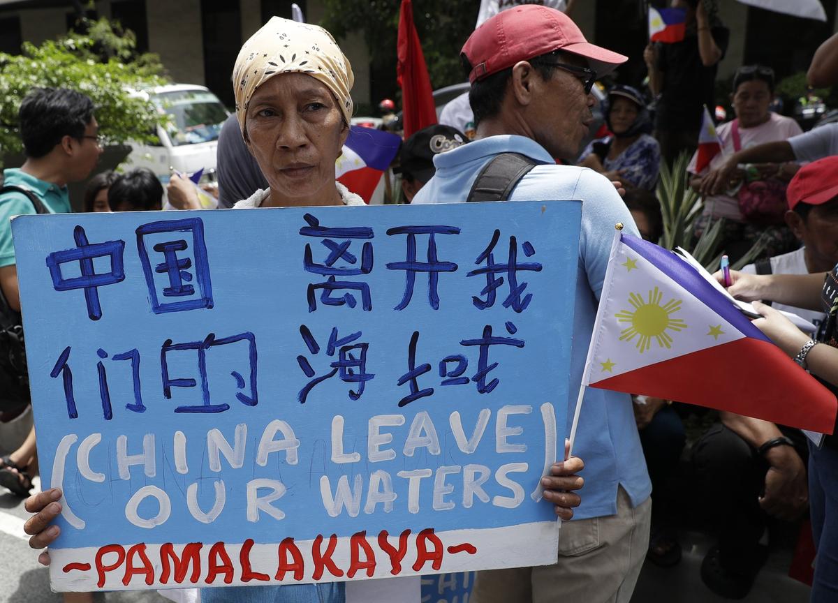 A protester holds a slogan during a rally outside the Chinese Consulate in the financial district of Makati, metropolitan Manila, Philippines to mark Independence Day on June 12, 2019. The Philippine defense secretary says an anchored Filipino fishing boat has sunk in the disputed South China Sea after being hit by a suspected Chinese vessel which then abandoned the 22 Filipino crewmen. (Aaron Favila/AP)