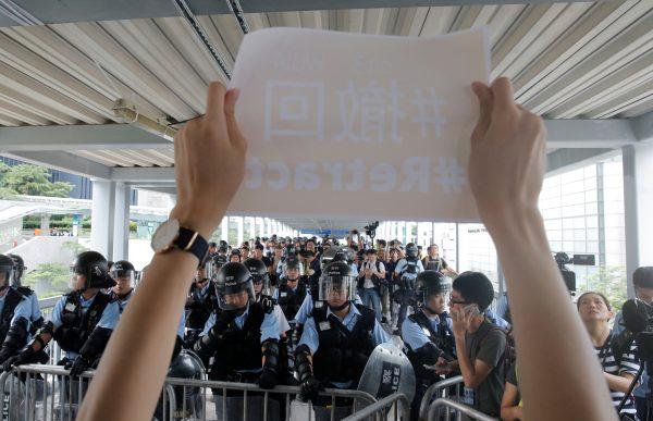 Police block a footbridge leading to the Legislative Council as a protester holds a sign in Hong Kong, on June 13, 2019. (Thomas Peter/Reuters)