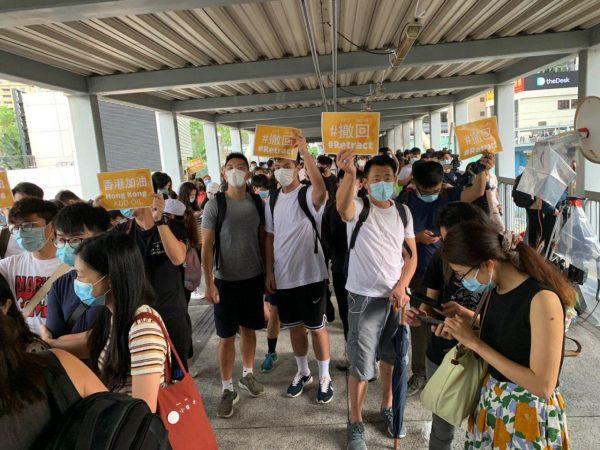 Protestors hold up signs in protest against a proposed extradition bill at the Citic Bridge in Hong Kong on June 13, 2019. (Li Yi/The Epoch Times)