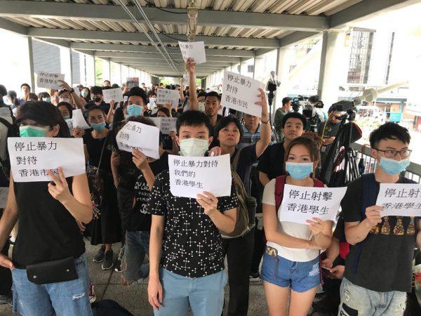 Protesters hold up signs that read “Stop Violence Against Hong Kong Citizens” and “Stop Shooting At Hong Kong Students” at the Citic Bridge in Hong Kong on June 13, 2019. (Cai Wenwen/The Epoch Times)