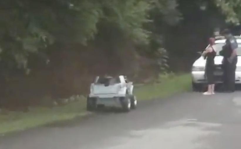 A screengrab shows a toy car on the side of the road in South Carolina as a woman talks to a police officer. (Screengrab/Travis Watkins/Youtube)