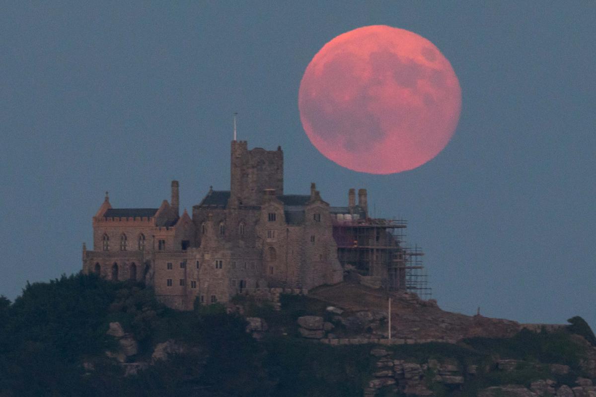 A "Strawberry Full Moon" rises behind St Michael's Mount in Marazion near Penzance on June 28, 2018 in Cornwall, England. (©Getty Images | <a href="https://www.gettyimages.com/detail/news-photo/full-moon-rises-behind-st-michaels-mount-in-marazion-near-news-photo/986813674?adppopup=true">Matt Cardy</a>)