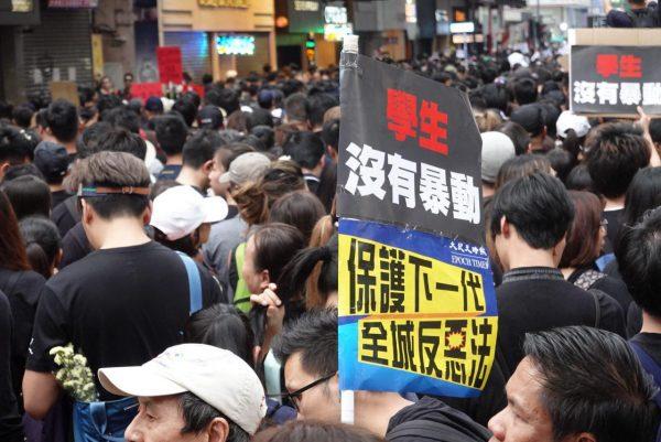 People at Times Square in Hong Kong try to join the march on June 16, 2019. One person held a slogan that said “Students have not rioted. Protect the next generation. Entire city against evil law.” (Yu Gang/The Epoch Times)