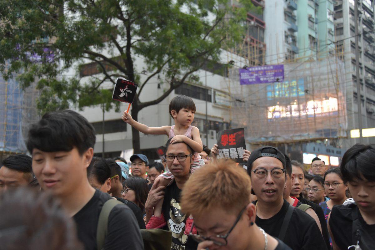 A girl hods a blacked Hong Kong flag among the protesters who demand on the extradition bill to be fully withdrawn in Hong Kong, on June 16, 2019. (Weili Guo/The Epoch Times)
