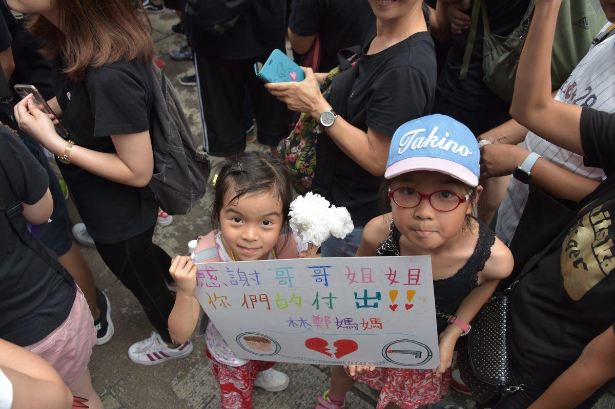 Two girls holding a hand made sign expressing appreciation to the protesters who gathered in hundreds of thousands on Hong Kong streets in protest of the proposed extradition bill, demanding it to be withdrawn, on June 16, 2019. (Weili Guo/The Epoch Times)