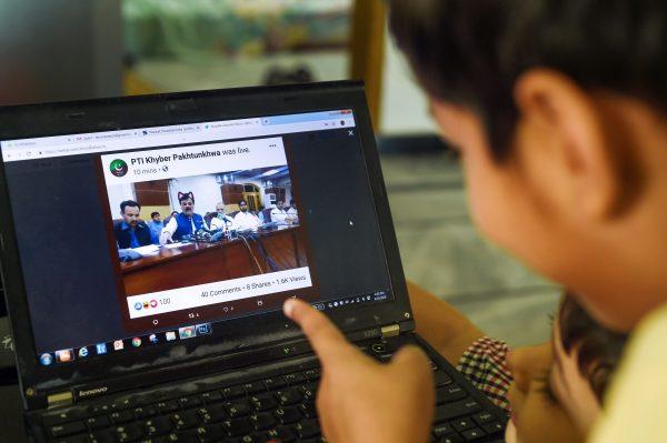 Pakistani children point at a computer screen showing a screen grab of a press conference attended by provincial minister Shaukat Yousafzai and streamed live on social media, in Islamabad on June 15, 2019. (Farooq Naeem/AFP/Getty Images)