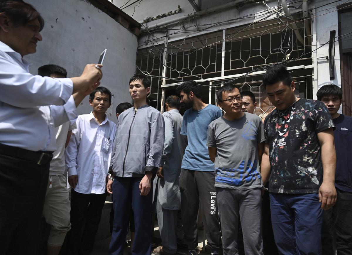 A Pakistani official takes pictures of detained Chinese nationals on alleged involvement in a trafficking gang to lure Pakistani women into fake marriages, arrive at a court in Islamabad, Pakistan on May 9, 2019. (B.K. Bangash/AP)