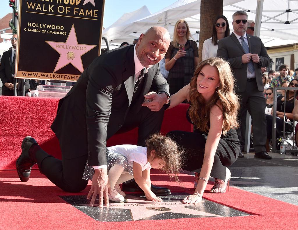 Dwayne Johnson, Lauren Hashian, and their daughter Jasmine touch Johnson's star on the Hollywood Walk of Fame in 2017 (©Getty Images | <a href="https://www.gettyimages.com/detail/news-photo/actor-dwayne-johnson-jasmine-johnson-and-singer-lauren-news-photo/891923144?adppopup=true">Alberto E. Rodriguez</a>)