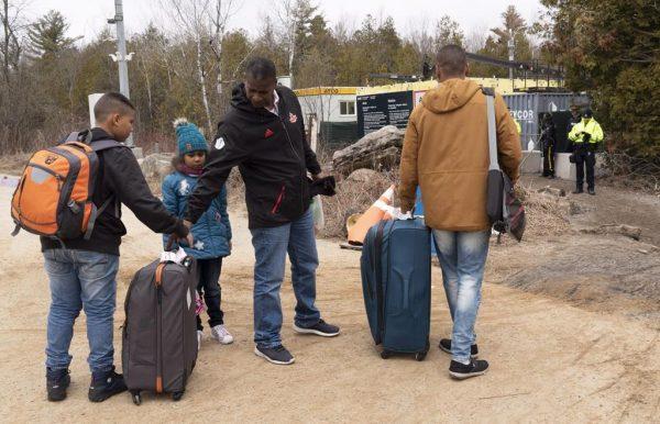 A family, claiming to be from Colombia, gets set to cross the border into Canada from the United States as asylum seekers on April 18, 2018 near Champlain, NY. (Paul Chiasson/The Canadian Press)