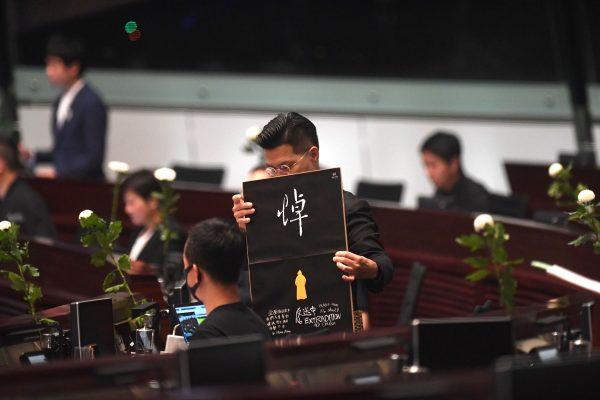 Pro-democracy lawmaker Gary Fan (C) holds a placard as he and other pro-democracy lawmakers hold five minutes of silence in the Legislative Council in Hong Kong on June 19, 2019, for a man who fell to his death on June 15 during a protest against a controversial extradition bill. (Anthony Wallace/AFP/Getty Images)