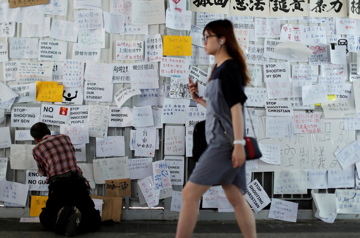 A man sticks notes on the wall near the Legislative Council building, as people gather to wait for a government announcement regarding the proposed extradition bill, in Hong Kong, China on June 15, 2019. (Jorge Silva/Reuters)