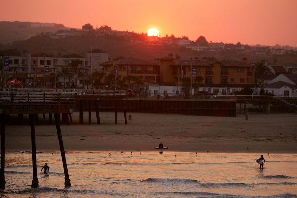 Local surfers walk into the waves as the sun rises at Pismo Beach, California, on Aug. 14, 2009. (Ezra Shaw/Getty Images)