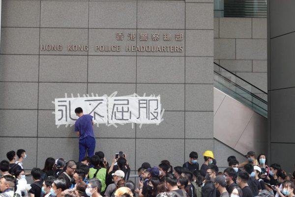 One protester puts up the words “Never Surrender” in Chinese on the wall of the Hong Kong Police Headquarters on June 21, 2019. (Yu Gang/The Epoch Times)