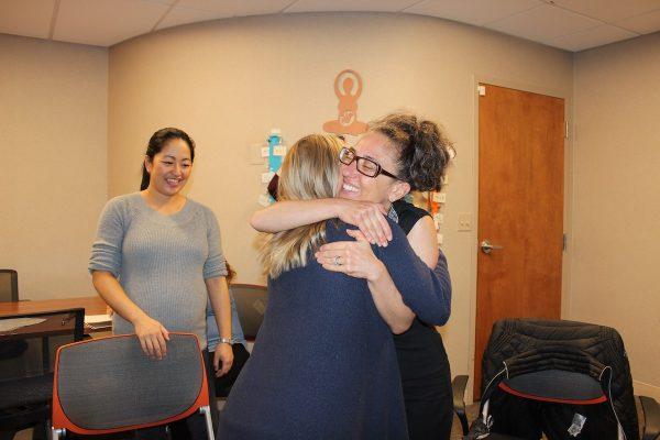 Midwife Ariel Yellin Derringer hugs Grace Tuman at a session of CenteringPregnancy at Northwestern Medicine, as Sara Choh looks on. (Jenny Gold/Kaiser Health News)