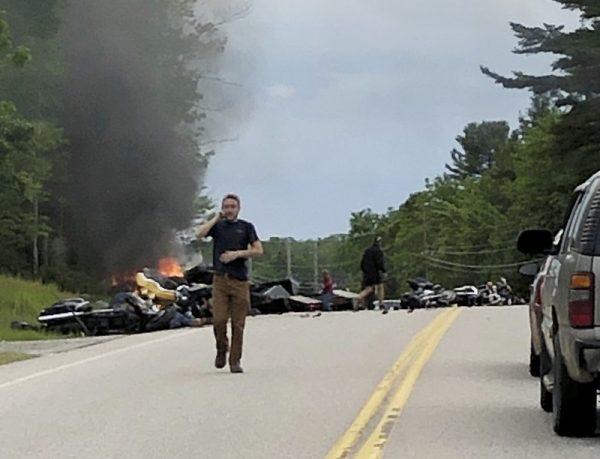 This photo provided by Miranda Thompson shows a man talking on his cellphone at the scene where several motorcycles and a pickup truck collided on a rural, two-lane highway in Randolph, N.H., on June 21, 2019. (Miranda Thompson via AP)