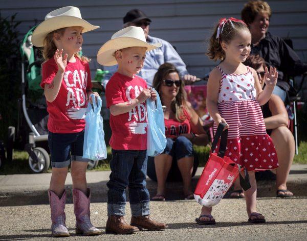 Children wave during a Canada Day parade in Cremona, Alta., on July 1, 2018. (Jeff McIntosh/The Canadian Press)