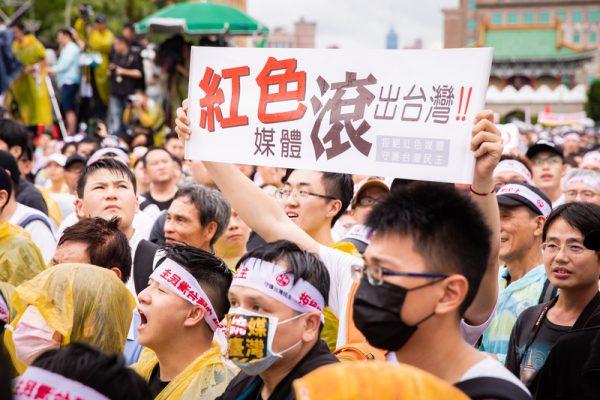 A protester holds up a sign with the words "Red Media Get Out of Taiwan" in Chinese in a rally in Taipei, Taiwan, on June 23, 2019. (Chen Pochou/The Epoch Times)