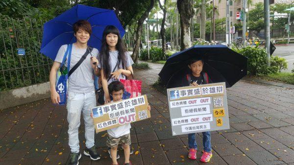 Children hold up signs that say "Red Media Out" and "Safeguard Taiwan's Democracy" as they join their parents in a rally in Taipei, on June 23, 2019. (Eugenia Lee/The Epoch Times)