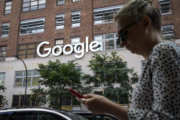 A woman looks at her smartphone as she walks past Google Building in New York on June 3, 2019. (Drew Angerer/Getty Images)
