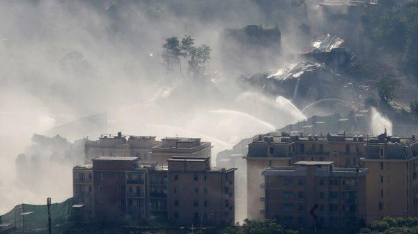 Fire hoses spray water to reduce dust triggered by the planned blast which demolished the remaining spans of the Morandi bridge, in Genoa, Italy, on June 28, 2019. (Antonio Calanni/AP Photo)<br/>(AP Photo/Antonio Calanni)