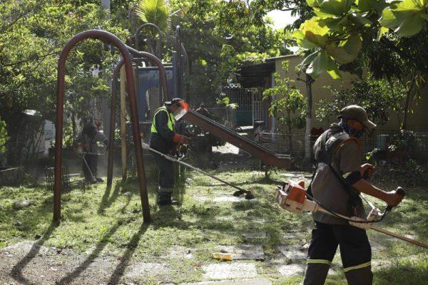 Municipal workers mow the lawn near a derelict swing set that is part of the Alta Vista neighborhood where migrant Oscar Martinez Ramirez and his two-year-old daughter Valeria lived, San Martin, El Salvador on June 26, 2019. (Salvador Melendez/Photo via AP)
