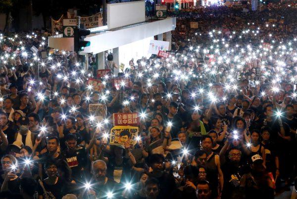 Anti-extradition bill protesters use the flashlights from their phones as they march during the anniversary of Hong Kong's handover to China in Hong Kong, on July 1, 2019. (Tyrone Siu/Reuters)