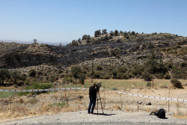 A cameraman films next to a slope where a missile struck, in Tashkent (also known as Vouno), in northern Cyprus on July 1, 2019. (Yiannis Kourtoglou/Reuters)