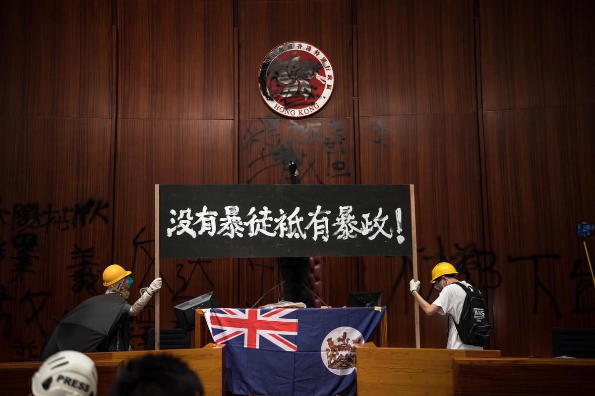 Protesters deface the Hong Kong logo at the Legislative Council to protest against the extradition bill on July 1, 2019 in Hong Kong, China. The black banner read: “There are no rioters, only violent regimes.” (Billy H.C. Kwok/Getty Images)