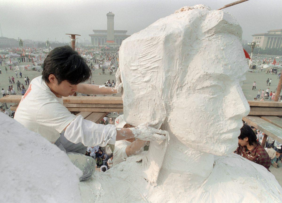 A student from an art institute plasters the neck of the "Goddess of Democracy" statue, a replica of the New York Statue of Liberty in Tiananmen Square in Beijing, China, on May 30, 1989. (CATHERINE HENRIETTE/AFP/Getty Images)