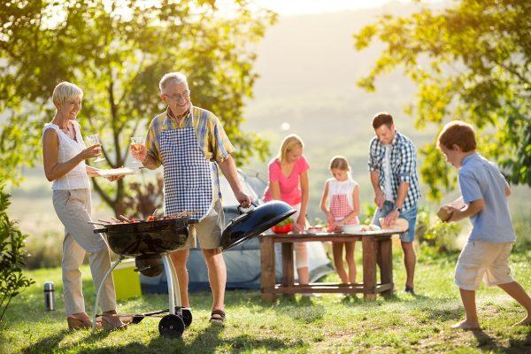 Happy family camping and cooking bbq. (Shutterstock)