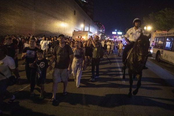 A Chicago Police Department (CPD) officer guard people as they stream out of Chicago's Navy Pier after reports of stabbings and threatening injuries after the 4th of July celebrations. (Amr Alfiky/Photo via AP)