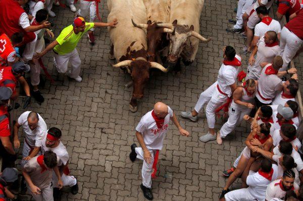 Revelers sprint in front of steers during the first running of the bulls at the San Fermin festival in Pamplona, Spain, on July 7, 2019. (Jon Nazca/Reuters)
