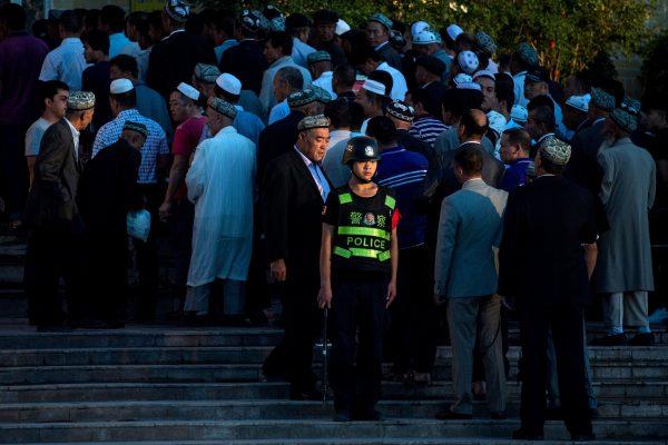 A policeman standing guard as Muslims arrive for the Eid al-Fitr morning prayer at the Id Kah Mosque in Kashgar in Xinjiang, China, on June 26, 2017. (Johannes Eisele/AFP/Getty Images)