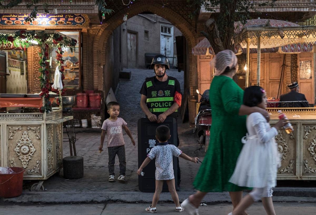 Ethnic Uyghur children joke as they taunt a local police officer in the old town of Kashgar, in the far western Xinjiang province, China, on June 29, 2017. (Kevin Frayer/Getty Images)