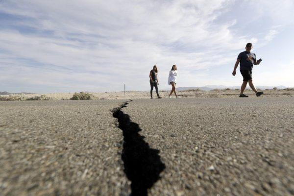 Visitors cross highway 178 next to a crack left on the road by an earthquake near Ridgecrest, Calif. on July 7, 2019. (Marcio Jose Sanchez/AP Photo)