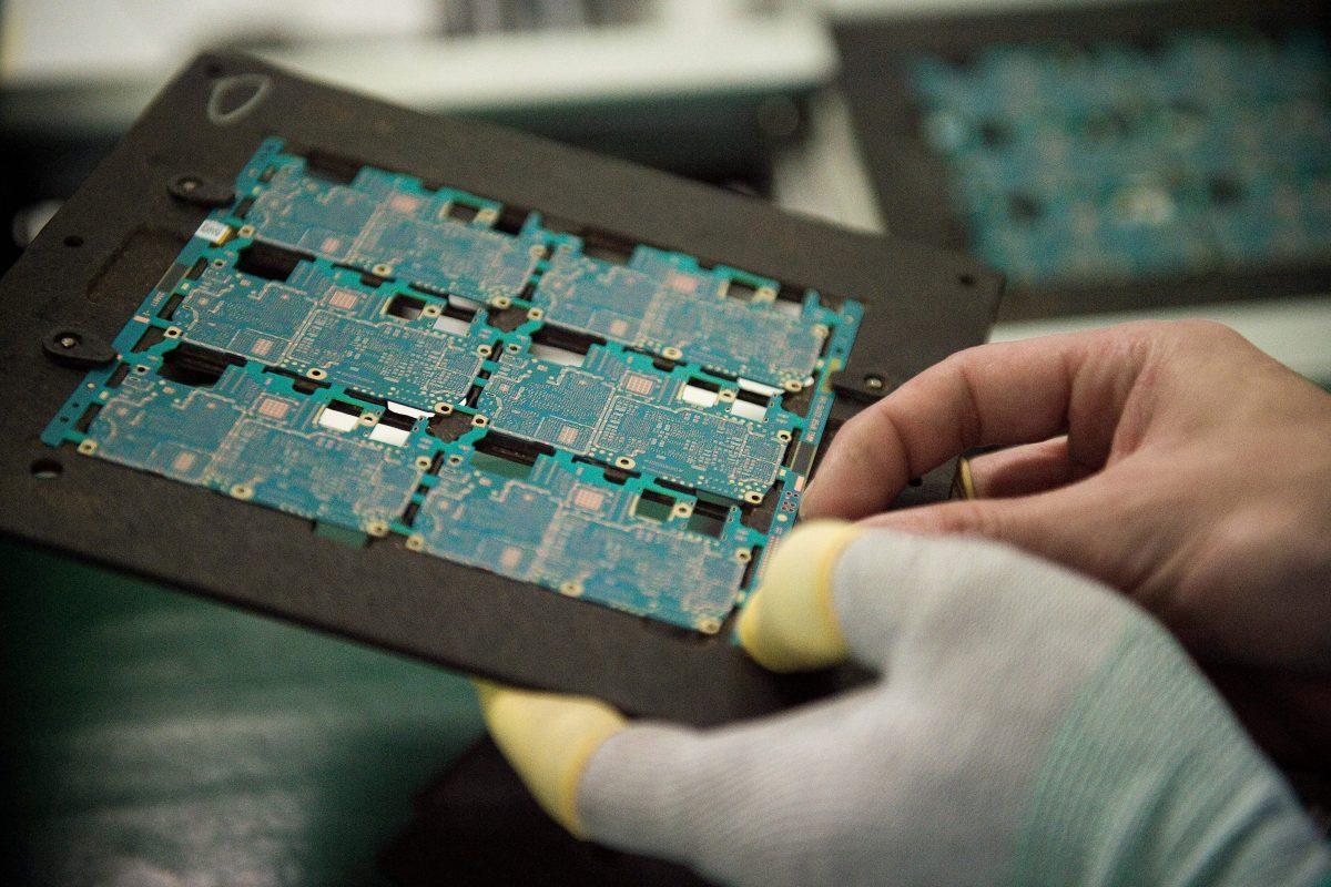 Smartphone chip component circuits are handled by a worker at a factory in Dongguan, Guangdong Province, China, on May 8, 2017. (Nicolas Asfouri/AFP/Getty Images)