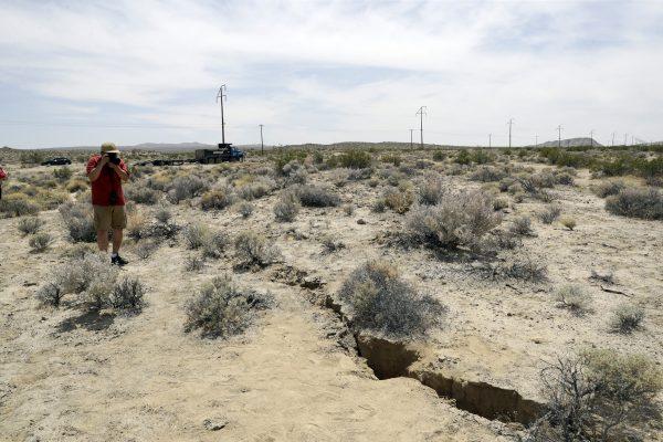 A visitor takes a photo of a crack on the ground following recent earthquakes outside of Ridgecrest, Calif., on July 7, 2019. (Marcio Jose Sanchez/AP Photo)